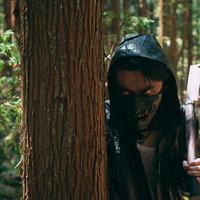 木陰に隠れて隙きをうかがう覆面の野盗が刃物を手に待ち伏せの写真