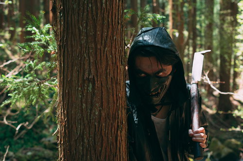 木陰に隠れて隙きをうかがう覆面の野盗が刃物を手に待ち伏せ