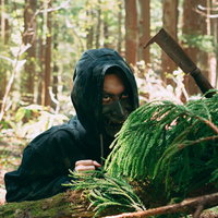 山林に潜む野盗の男性フード姿の不審な潜伏風景の写真