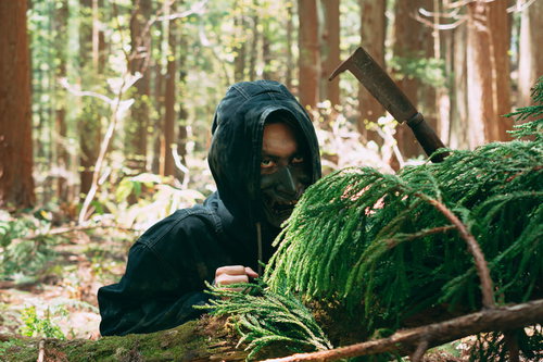 山林に潜む野盗の男性フード姿の不審な潜伏風景