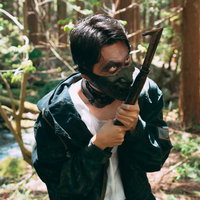 刃物を舐めるように見つめる黒マスクの山賊の男性の写真