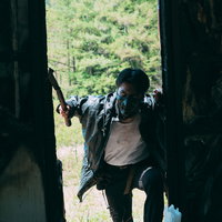 廃屋の窓枠に身を隠し周囲を監視する不審な男性の姿と脅迫的な表情の写真