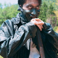 黒マスクと迷彩服に身を包む狂気的な男性の屋外撮影の写真