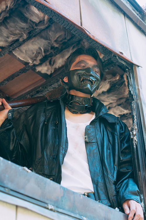 黒いデビルマスクと革ジャケットを着た男性