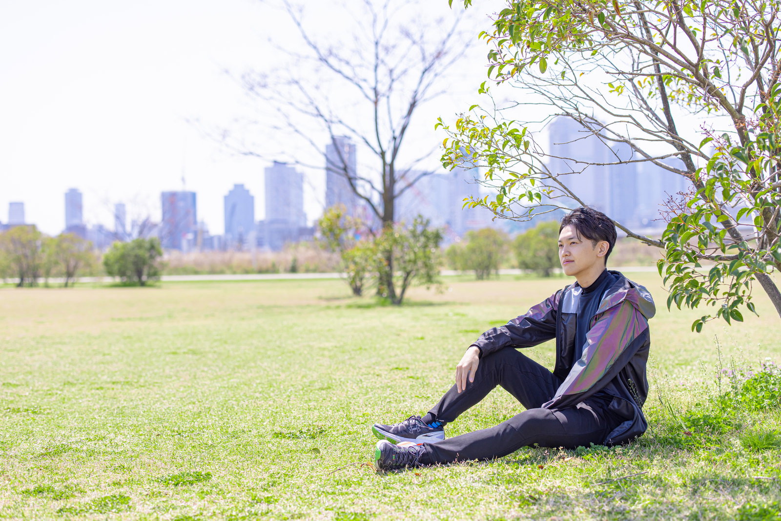 緑の芝生の上で休憩するランニングウェア姿の男性［モデル：花和瞭］