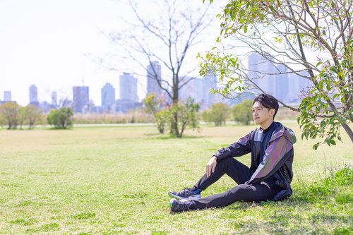 野原で休息するランニング中の男性