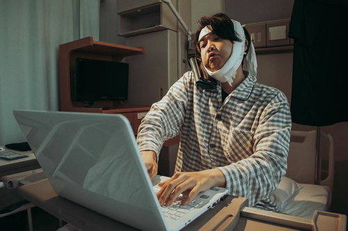 ひげそり失敗で病院入院、頭部包帯姿でノートパソコンを操作する男性