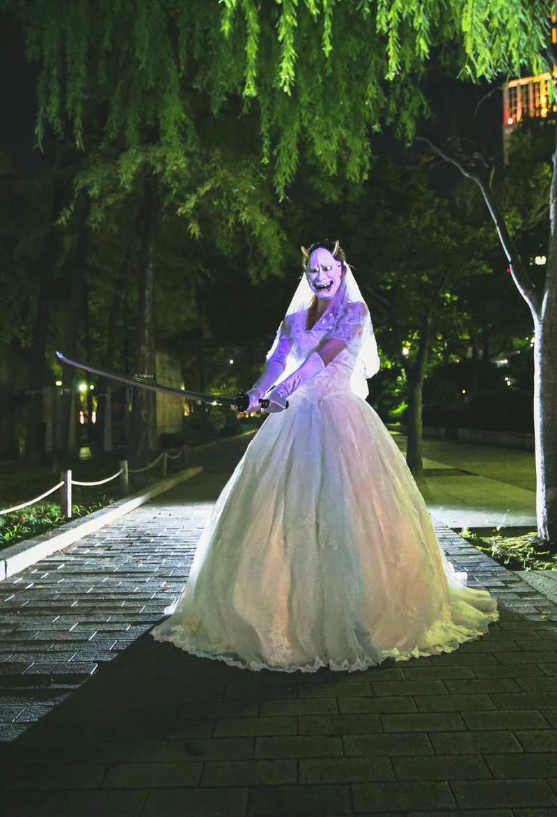 夜道で般若のお面をつけて日本刀を振りかざす白いウェディングドレスの女性［モデル：モデルリリース］