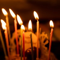 誕生日ケーキに立てられたおめでとうのロウソクの写真
