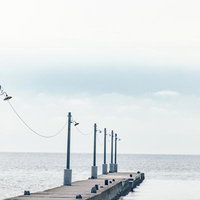 曇空に延びる原岡桟橋のレトロな木製桟橋と海岸風景の写真
