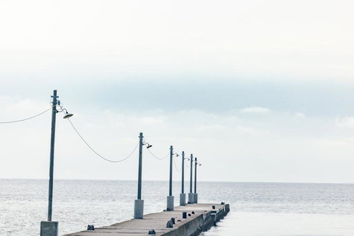 曇空に延びる原岡桟橋のレトロな木製桟橋と海岸風景