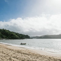 晴れた日の砂浜に停泊するボートと青い海の風景の写真