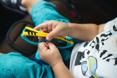 黄色いフレームのおもちゃのサングラスを手に取る子供