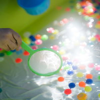 カラフルなスーパーボールすくい、緑色のポイで夏祭りの屋台遊びの写真