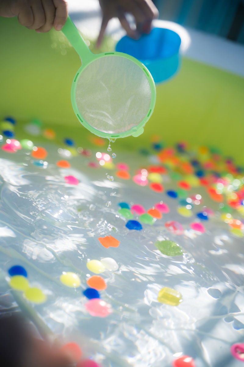 水に浮かぶカラフルなスーパーボールと紙ポイのスーパーボールすくいの様子