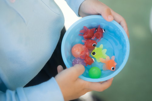 夏祭りの出店で金魚すくいの景品を手にする子供