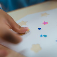 シールをペタペタ貼る子供の手で星型やヒトデ型を貼るの写真