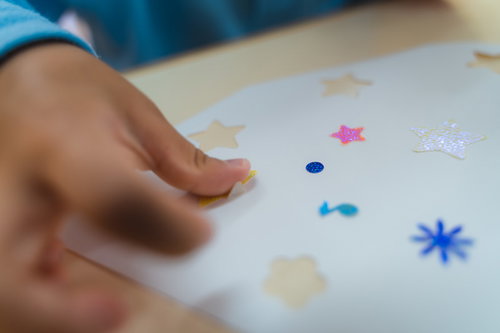 シールをペタペタ貼る子供の手で星型やヒトデ型を貼る