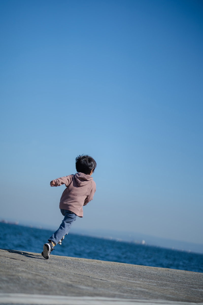 青空の下、海岸を元気よく走る子供