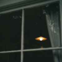 窓ガラス越しに見た暖色の間接照明と室内照明器具の映り込みの写真