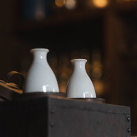 白い陶器の徳利に注いだ熱燗、木製テーブルに2本並べた日本酒の写真