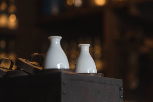 白い陶器の徳利に注いだ熱燗、木製テーブルに2本並べた日本酒