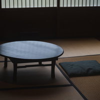 畳の和室に置かれた丸いちゃぶ台と黒い座布団の写真