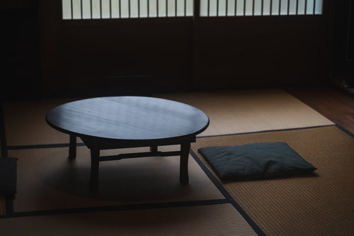 畳の和室に置かれた丸いちゃぶ台と黒い座布団
