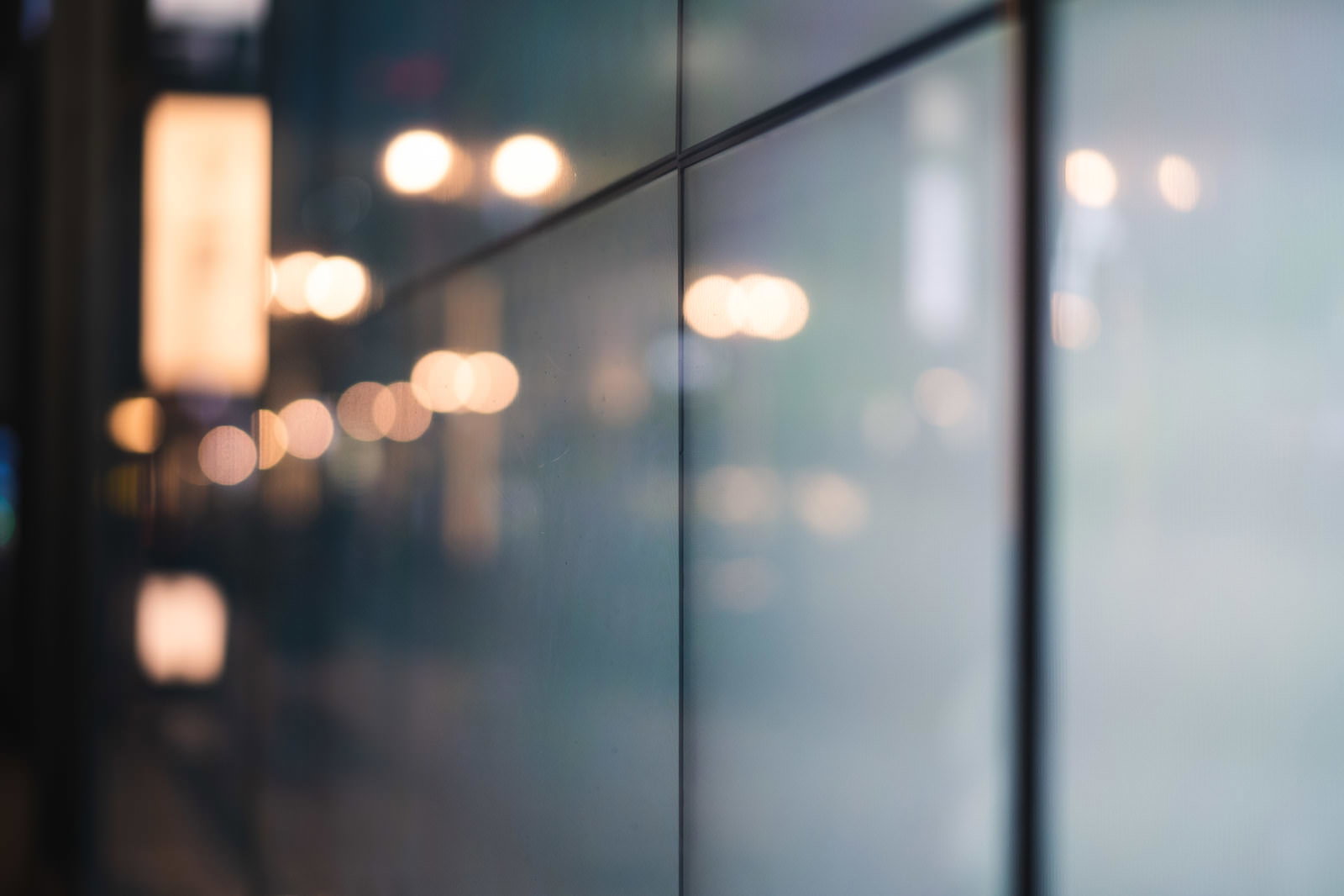ガラス面に反射した街の灯りがボケて映る夜景