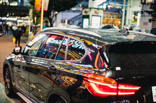 黒塗りの車両に映り込むネオンとブレーキランプの光