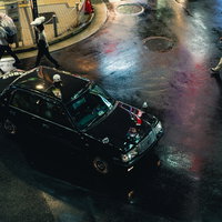 雨が降る繁華街でタクシーが停車する街並みの写真