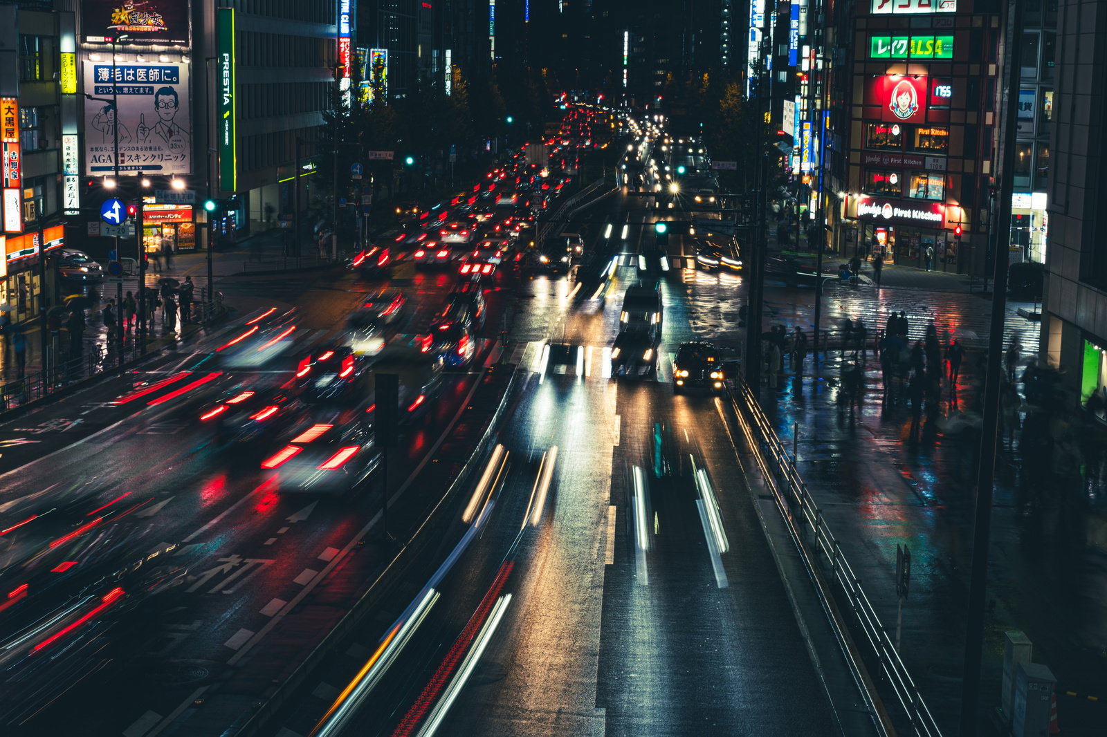 雨の夜道で赤いテールランプを点灯させながら走る車と歩行者のシルエット