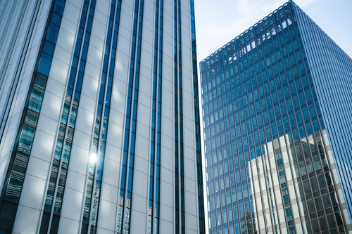 カーテンウォールに反射する複数のビル群と都市風景