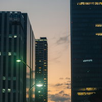 夕焼け空に佇む都会の高層ビル群と窓明かりの写真
