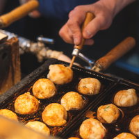 出店の鉄板プレートで焼くたこ焼き風景の写真