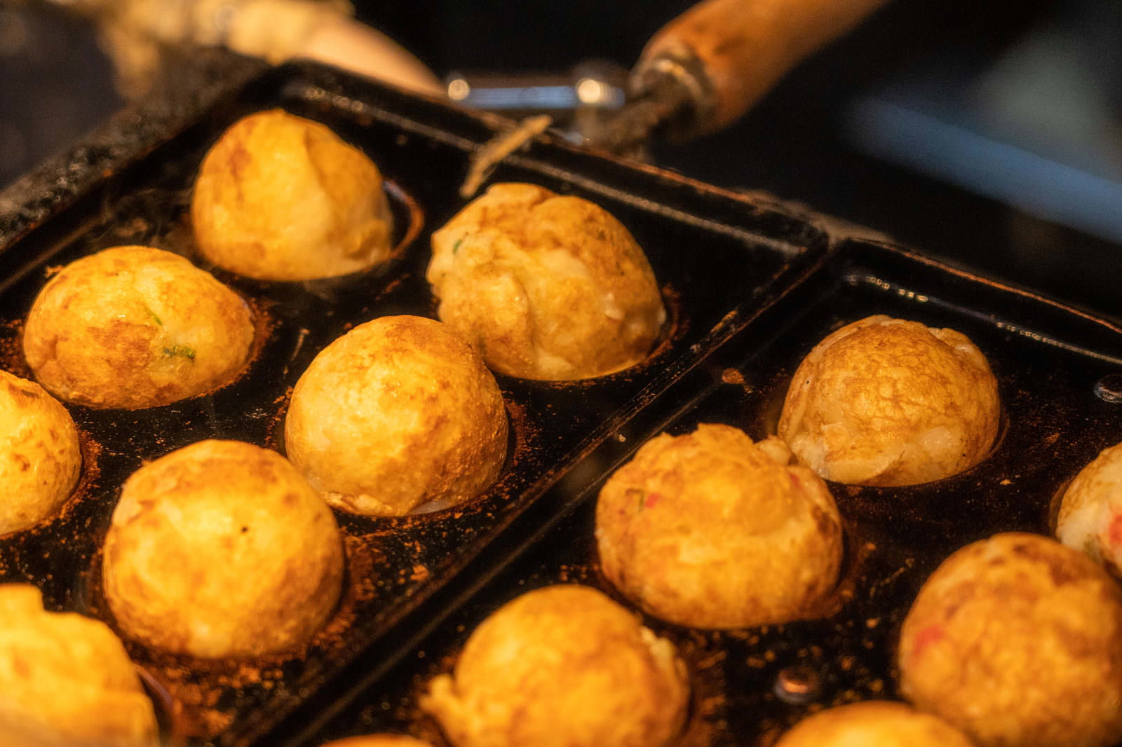 鉄板プレート上で焼き上がった黄金色のたこ焼きが並んでいる様子