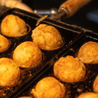 屋台の鉄板で焼き上がる完成間際のたこ焼きの写真