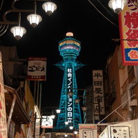 夜にライトアップされた通天閣と周囲の店看板の写真