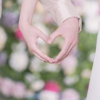2人の手で作るハートと結婚指輪の写真