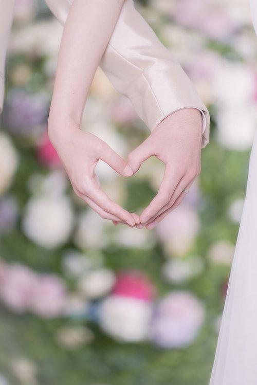 結婚指輪をつけた新郎新婦の手で作るハート型