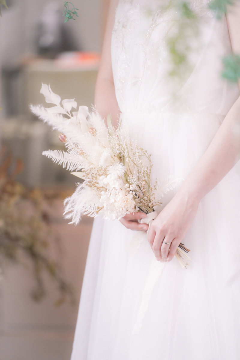 白いウェディングドレスを着た花嫁がドライフラワーのブーケを持っている［モデル：たけべともこ］