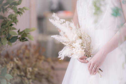 ブーケを持った白いウェディングドレスを着た女性の手元