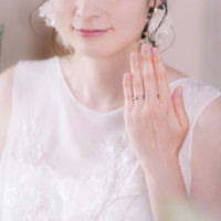 薬指に輝く結婚指輪を見せるウェディングドレス姿の花嫁の写真