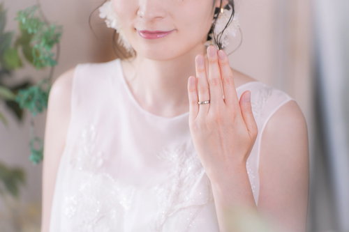 薬指に輝く結婚指輪を見せるウェディングドレス姿の花嫁
