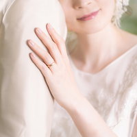 新郎の肩に寄りかかるウェディングドレスの新婦の写真