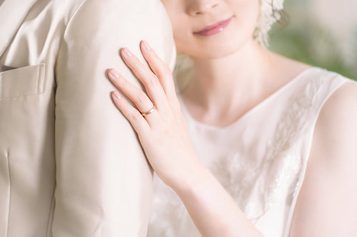 新郎の肩に寄りかかるウェディングドレスの新婦