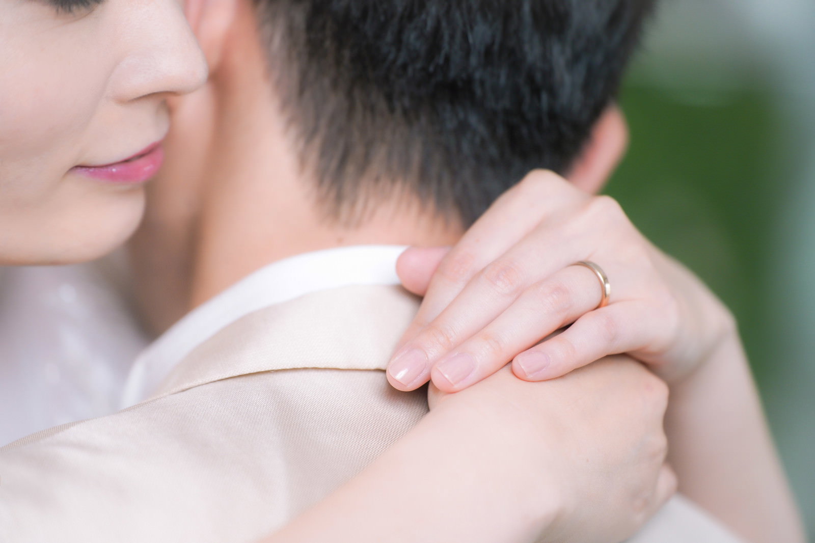 白いドレスの女性が男性を抱きしめながら結婚指輪を見つめている［モデル：たけべともこ］