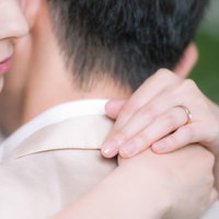 白いドレス姿で彼を抱きしめながら結婚指輪を見つめる女性の写真