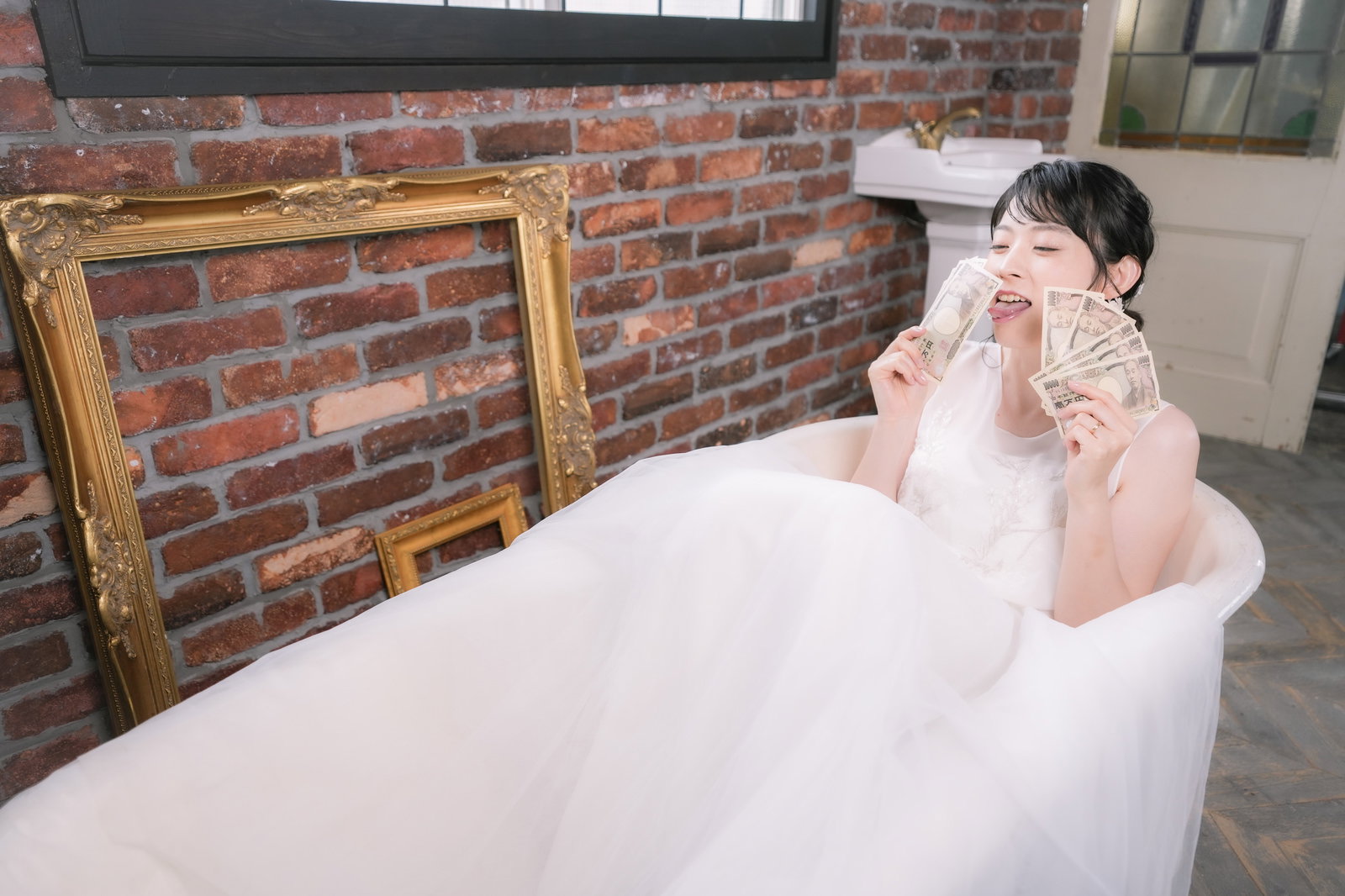 白いウェディングドレスを着て片手を頬に当ててポーズを取る女性［モデル：たけべともこ］