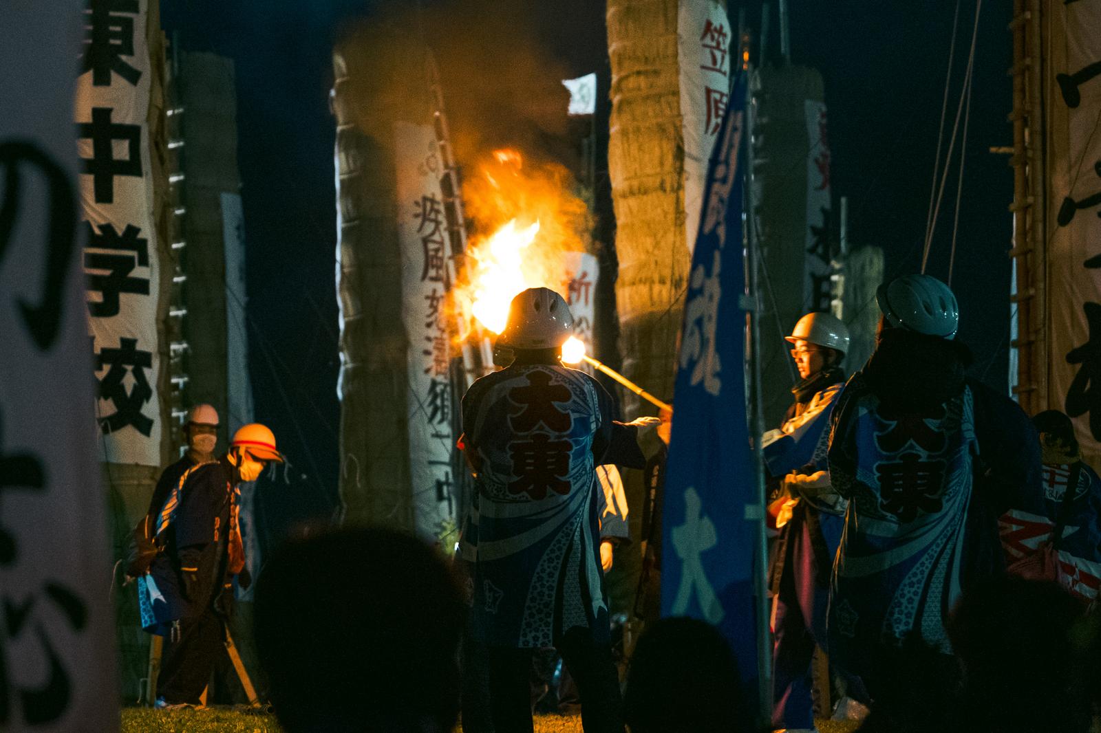 夜の須賀川市で松明に点火する青年団と炎上がる火祭りの場面